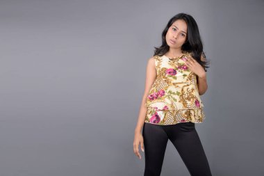 Çiçekli bir bluz, siyah tayt ve siyah topuklu giyen çekici genç bir kadın, neşeli yüz ifadeleri ve farklı duygularla poz veriyor, modern tarzı, zarafeti sergiliyor..