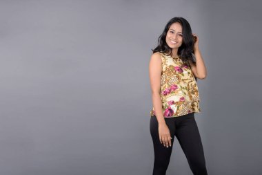 Çiçekli bir bluz, siyah tayt ve siyah topuklu giyen çekici genç bir kadın, neşeli yüz ifadeleri ve farklı duygularla poz veriyor, modern tarzı, zarafeti sergiliyor..