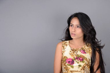 Çiçekli bir bluz, siyah tayt ve siyah topuklu giyen çekici genç bir kadın, neşeli yüz ifadeleri ve farklı duygularla poz veriyor, modern tarzı, zarafeti sergiliyor..