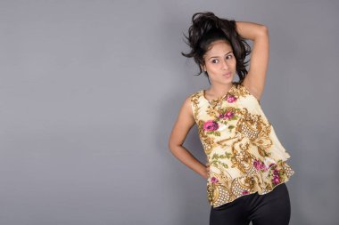 Çiçekli bir bluz, siyah tayt ve siyah topuklu giyen çekici genç bir kadın, neşeli yüz ifadeleri ve farklı duygularla poz veriyor, modern tarzı, zarafeti sergiliyor..