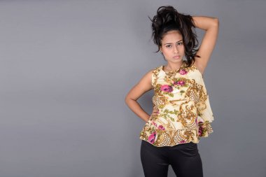 Çiçekli bir bluz, siyah tayt ve siyah topuklu giyen çekici genç bir kadın, neşeli yüz ifadeleri ve farklı duygularla poz veriyor, modern tarzı, zarafeti sergiliyor..