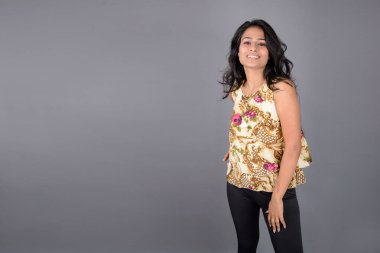 Çiçekli bir bluz, siyah tayt ve siyah topuklu giyen çekici genç bir kadın, neşeli yüz ifadeleri ve farklı duygularla poz veriyor, modern tarzı, zarafeti sergiliyor..