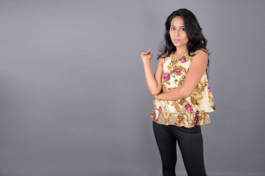 Çiçekli bir bluz, siyah tayt ve siyah topuklu giyen çekici genç bir kadın, neşeli yüz ifadeleri ve farklı duygularla poz veriyor, modern tarzı, zarafeti sergiliyor..