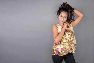 Çiçekli bir bluz, siyah tayt ve siyah topuklu giyen çekici genç bir kadın, neşeli yüz ifadeleri ve farklı duygularla poz veriyor, modern tarzı, zarafeti sergiliyor..