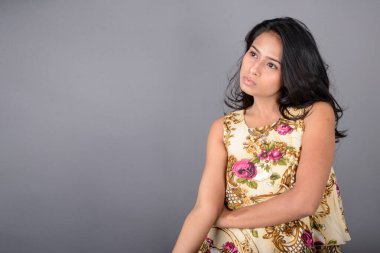 Çiçekli bir bluz, siyah tayt ve siyah topuklu giyen çekici genç bir kadın, neşeli yüz ifadeleri ve farklı duygularla poz veriyor, modern tarzı, zarafeti sergiliyor..