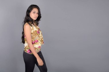 Çiçekli bir bluz, siyah tayt ve siyah topuklu giyen çekici genç bir kadın, neşeli yüz ifadeleri ve farklı duygularla poz veriyor, modern tarzı, zarafeti sergiliyor..