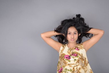 Çiçekli bir bluz, siyah tayt ve siyah topuklu giyen çekici genç bir kadın, neşeli yüz ifadeleri ve farklı duygularla poz veriyor, modern tarzı, zarafeti sergiliyor..