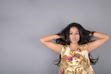 Çiçekli bir bluz, siyah tayt ve siyah topuklu giyen çekici genç bir kadın, neşeli yüz ifadeleri ve farklı duygularla poz veriyor, modern tarzı, zarafeti sergiliyor..