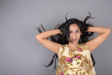 Çiçekli bir bluz, siyah tayt ve siyah topuklu giyen çekici genç bir kadın, neşeli yüz ifadeleri ve farklı duygularla poz veriyor, modern tarzı, zarafeti sergiliyor..