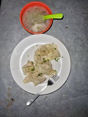 Vejetaryen Momo buğulaması. Nepal Geleneksel Yemeği Momo sebzelerle dolduruldu ve sonra seramik siyah tabakta sosla pişirilip servis edildi. Konuya özen gösterildi.