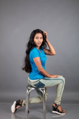 Genç bir kadın özgüvenle mavi tişört, sıkıntılı kot pantolon, topuklu ayakkabı giyerek poz veriyor, cazibe ve zarafetle gelişigüzel bir şehir tarzı sergiliyor, saç bakımı, özgürlük, kendini ifade etme projesi için uygun.