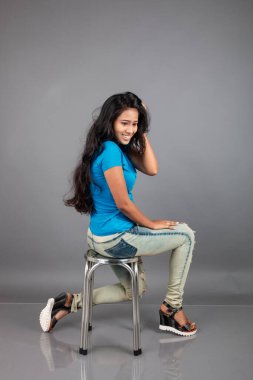 Genç bir kadın özgüvenle mavi tişört, sıkıntılı kot pantolon, topuklu ayakkabı giyerek poz veriyor, cazibe ve zarafetle gelişigüzel bir şehir tarzı sergiliyor, saç bakımı, özgürlük, kendini ifade etme projesi için uygun.