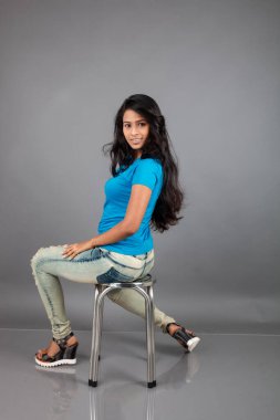 Genç bir kadın özgüvenle mavi tişört, sıkıntılı kot pantolon, topuklu ayakkabı giyerek poz veriyor, cazibe ve zarafetle gelişigüzel bir şehir tarzı sergiliyor, saç bakımı, özgürlük, kendini ifade etme projesi için uygun.