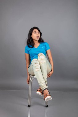 Genç bir kadın özgüvenle mavi tişört, sıkıntılı kot pantolon, topuklu ayakkabı giyerek poz veriyor, cazibe ve zarafetle gelişigüzel bir şehir tarzı sergiliyor, saç bakımı, özgürlük, kendini ifade etme projesi için uygun.