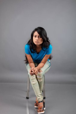 Genç bir kadın özgüvenle mavi tişört, sıkıntılı kot pantolon, topuklu ayakkabı giyerek poz veriyor, cazibe ve zarafetle gelişigüzel bir şehir tarzı sergiliyor, saç bakımı, özgürlük, kendini ifade etme projesi için uygun.