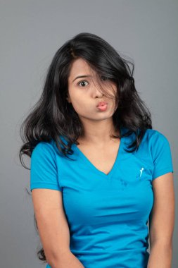 Genç bir kadın özgüvenle mavi tişört, sıkıntılı kot pantolon, topuklu ayakkabı giyerek poz veriyor, cazibe ve zarafetle gelişigüzel bir şehir tarzı sergiliyor, saç bakımı, özgürlük, kendini ifade etme projesi için uygun.