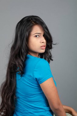 Genç bir kadın özgüvenle mavi tişört, sıkıntılı kot pantolon, topuklu ayakkabı giyerek poz veriyor, cazibe ve zarafetle gelişigüzel bir şehir tarzı sergiliyor, saç bakımı, özgürlük, kendini ifade etme projesi için uygun.