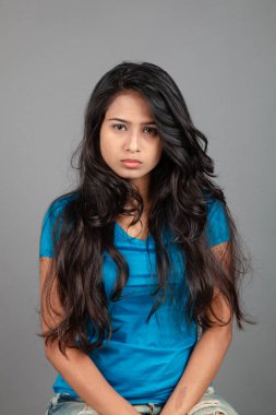 Genç bir kadın özgüvenle mavi tişört, sıkıntılı kot pantolon, topuklu ayakkabı giyerek poz veriyor, cazibe ve zarafetle gelişigüzel bir şehir tarzı sergiliyor, saç bakımı, özgürlük, kendini ifade etme projesi için uygun.