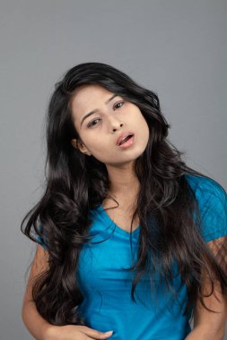 Genç bir kadın özgüvenle mavi tişört, sıkıntılı kot pantolon, topuklu ayakkabı giyerek poz veriyor, cazibe ve zarafetle gelişigüzel bir şehir tarzı sergiliyor, saç bakımı, özgürlük, kendini ifade etme projesi için uygun.