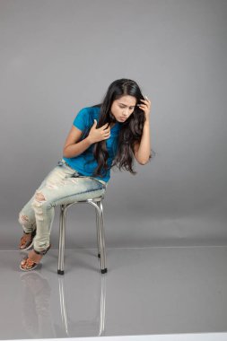 Genç bir kadın özgüvenle mavi tişört, sıkıntılı kot pantolon, topuklu ayakkabı giyerek poz veriyor, cazibe ve zarafetle gelişigüzel bir şehir tarzı sergiliyor, saç bakımı, özgürlük, kendini ifade etme projesi için uygun.