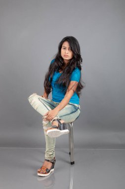 Genç bir kadın özgüvenle mavi tişört, sıkıntılı kot pantolon, topuklu ayakkabı giyerek poz veriyor, cazibe ve zarafetle gelişigüzel bir şehir tarzı sergiliyor, saç bakımı, özgürlük, kendini ifade etme projesi için uygun.