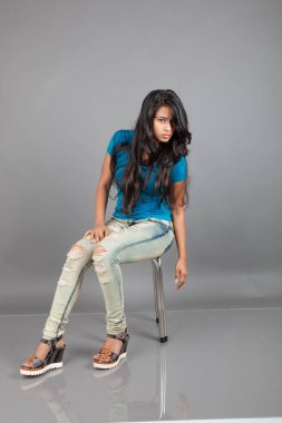 Genç bir kadın özgüvenle mavi tişört, sıkıntılı kot pantolon, topuklu ayakkabı giyerek poz veriyor, cazibe ve zarafetle gelişigüzel bir şehir tarzı sergiliyor, saç bakımı, özgürlük, kendini ifade etme projesi için uygun.