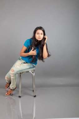 Genç bir kadın özgüvenle mavi tişört, sıkıntılı kot pantolon, topuklu ayakkabı giyerek poz veriyor, cazibe ve zarafetle gelişigüzel bir şehir tarzı sergiliyor, saç bakımı, özgürlük, kendini ifade etme projesi için uygun.