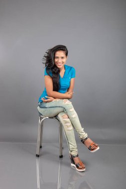 Genç bir kadın özgüvenle mavi tişört, sıkıntılı kot pantolon, topuklu ayakkabı giyerek poz veriyor, cazibe ve zarafetle gelişigüzel bir şehir tarzı sergiliyor, saç bakımı, özgürlük, kendini ifade etme projesi için uygun.