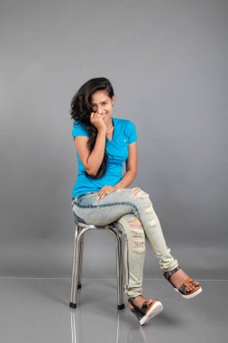 Genç bir kadın özgüvenle mavi tişört, sıkıntılı kot pantolon, topuklu ayakkabı giyerek poz veriyor, cazibe ve zarafetle gelişigüzel bir şehir tarzı sergiliyor, saç bakımı, özgürlük, kendini ifade etme projesi için uygun.