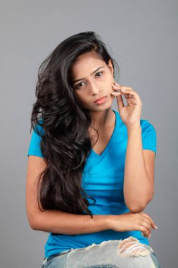 Genç bir kadın özgüvenle mavi tişört, sıkıntılı kot pantolon, topuklu ayakkabı giyerek poz veriyor, cazibe ve zarafetle gelişigüzel bir şehir tarzı sergiliyor, saç bakımı, özgürlük, kendini ifade etme projesi için uygun.