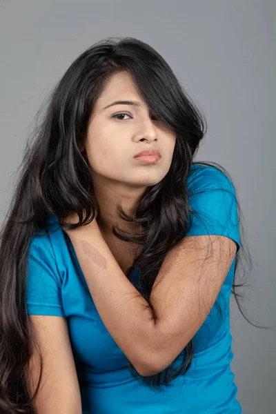 Genç bir kadın özgüvenle mavi tişört, sıkıntılı kot pantolon, topuklu ayakkabı giyerek poz veriyor, cazibe ve zarafetle gelişigüzel bir şehir tarzı sergiliyor, saç bakımı, özgürlük, kendini ifade etme projesi için uygun.