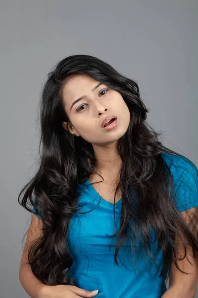 Genç bir kadın özgüvenle mavi tişört, sıkıntılı kot pantolon, topuklu ayakkabı giyerek poz veriyor, cazibe ve zarafetle gelişigüzel bir şehir tarzı sergiliyor, saç bakımı, özgürlük, kendini ifade etme projesi için uygun.