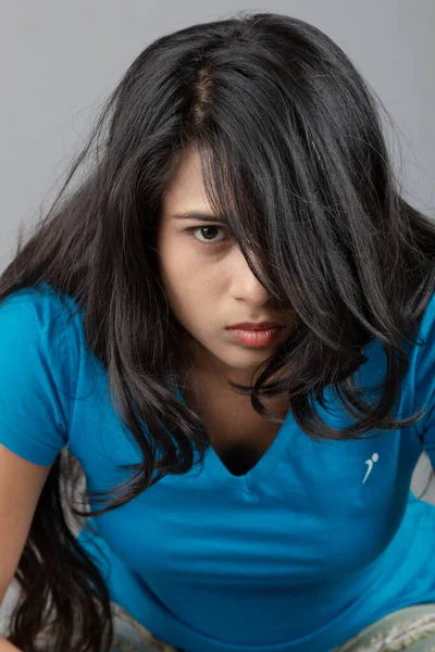 Genç bir kadın özgüvenle mavi tişört, sıkıntılı kot pantolon, topuklu ayakkabı giyerek poz veriyor, cazibe ve zarafetle gelişigüzel bir şehir tarzı sergiliyor, saç bakımı, özgürlük, kendini ifade etme projesi için uygun.