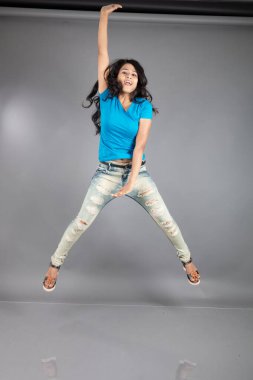 Genç bir kadın özgüvenle mavi tişört, sıkıntılı kot pantolon, topuklu ayakkabı giyerek poz veriyor, cazibe ve zarafetle gelişigüzel bir şehir tarzı sergiliyor, saç bakımı, özgürlük, kendini ifade etme projesi için uygun.