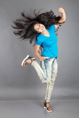 Genç bir kadın özgüvenle mavi tişört, sıkıntılı kot pantolon, topuklu ayakkabı giyerek poz veriyor, cazibe ve zarafetle gelişigüzel bir şehir tarzı sergiliyor, saç bakımı, özgürlük, kendini ifade etme projesi için uygun.