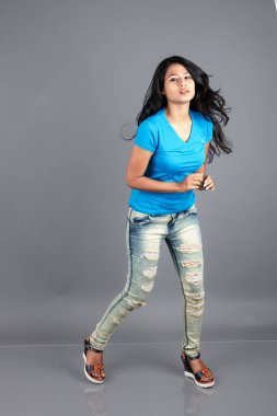 Genç bir kadın özgüvenle mavi tişört, sıkıntılı kot pantolon, topuklu ayakkabı giyerek poz veriyor, cazibe ve zarafetle gelişigüzel bir şehir tarzı sergiliyor, saç bakımı, özgürlük, kendini ifade etme projesi için uygun.