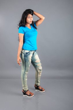 Genç bir kadın özgüvenle mavi tişört, sıkıntılı kot pantolon, topuklu ayakkabı giyerek poz veriyor, cazibe ve zarafetle gelişigüzel bir şehir tarzı sergiliyor, saç bakımı, özgürlük, kendini ifade etme projesi için uygun.