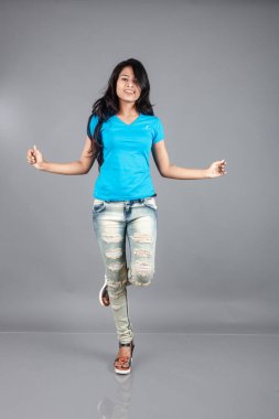 Genç bir kadın özgüvenle mavi tişört, sıkıntılı kot pantolon, topuklu ayakkabı giyerek poz veriyor, cazibe ve zarafetle gelişigüzel bir şehir tarzı sergiliyor, saç bakımı, özgürlük, kendini ifade etme projesi için uygun.