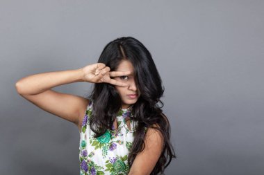 Kendine güvenen, çiçekli bluz giyen genç bir kadın zarif bir şekilde stüdyo ortamında poz veriyor. Güzelliğini, kendine güvenini ve tarzını sergiliyor. Onun uzun saçları zarif bir şekilde akıyor, resme hareketlilik ve canlılık katıyor.