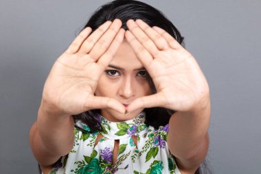 Kendine güvenen, çiçekli bluz giyen genç bir kadın zarif bir şekilde stüdyo ortamında poz veriyor. Güzelliğini, kendine güvenini ve tarzını sergiliyor. Onun uzun saçları zarif bir şekilde akıyor, resme hareketlilik ve canlılık katıyor.