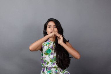 Kendine güvenen, çiçekli bluz giyen genç bir kadın zarif bir şekilde stüdyo ortamında poz veriyor. Güzelliğini, kendine güvenini ve tarzını sergiliyor. Onun uzun saçları zarif bir şekilde akıyor, resme hareketlilik ve canlılık katıyor.