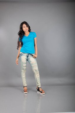 Genç bir kadın özgüvenle mavi tişört, sıkıntılı kot pantolon, topuklu ayakkabı giyerek poz veriyor, cazibe ve zarafetle gelişigüzel bir şehir tarzı sergiliyor, saç bakımı, özgürlük, kendini ifade etme projesi için uygun.,.