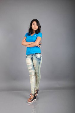 Genç bir kadın özgüvenle mavi tişört, sıkıntılı kot pantolon, topuklu ayakkabı giyerek poz veriyor, cazibe ve zarafetle gelişigüzel bir şehir tarzı sergiliyor, saç bakımı, özgürlük, kendini ifade etme projesi için uygun.,.