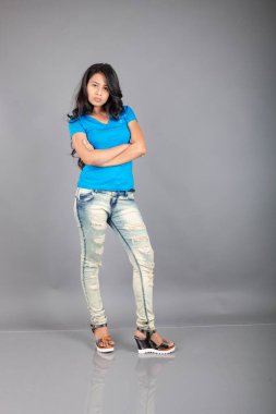 Genç bir kadın özgüvenle mavi tişört, sıkıntılı kot pantolon, topuklu ayakkabı giyerek poz veriyor, cazibe ve zarafetle gelişigüzel bir şehir tarzı sergiliyor, saç bakımı, özgürlük, kendini ifade etme projesi için uygun.,.