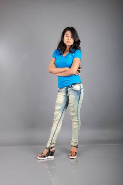 Genç bir kadın özgüvenle mavi tişört, sıkıntılı kot pantolon, topuklu ayakkabı giyerek poz veriyor, cazibe ve zarafetle gelişigüzel bir şehir tarzı sergiliyor, saç bakımı, özgürlük, kendini ifade etme projesi için uygun.,.