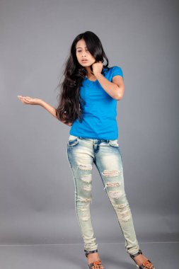 Genç bir kadın özgüvenle mavi tişört, sıkıntılı kot pantolon, topuklu ayakkabı giyerek poz veriyor, cazibe ve zarafetle gelişigüzel bir şehir tarzı sergiliyor, saç bakımı, özgürlük, kendini ifade etme projesi için uygun.,.