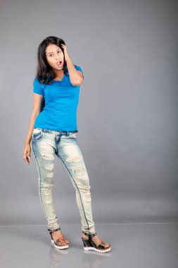 Genç bir kadın özgüvenle mavi tişört, sıkıntılı kot pantolon, topuklu ayakkabı giyerek poz veriyor, cazibe ve zarafetle gelişigüzel bir şehir tarzı sergiliyor, saç bakımı, özgürlük, kendini ifade etme projesi için uygun.,.