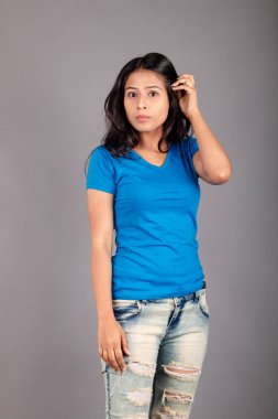 Genç bir kadın özgüvenle mavi tişört, sıkıntılı kot pantolon, topuklu ayakkabı giyerek poz veriyor, cazibe ve zarafetle gelişigüzel bir şehir tarzı sergiliyor, saç bakımı, özgürlük, kendini ifade etme projesi için uygun.,.