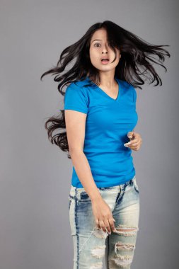 Genç bir kadın özgüvenle mavi tişört, sıkıntılı kot pantolon, topuklu ayakkabı giyerek poz veriyor, cazibe ve zarafetle gelişigüzel bir şehir tarzı sergiliyor, saç bakımı, özgürlük, kendini ifade etme projesi için uygun.,.