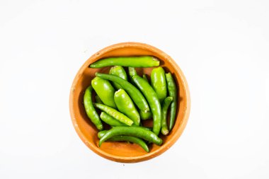 Beyaz arka planda el yapımı kil kasede sergilenen taze yeşil biber koleksiyonu.